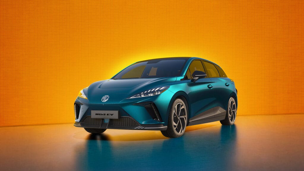 Auf diesem Bild ist ein türkisfarbenes MG4 EV Elektroauto vor einem leuchtend orangefarbenen, strukturierten Hintergrund auf einem reflektierenden Boden zu sehen.