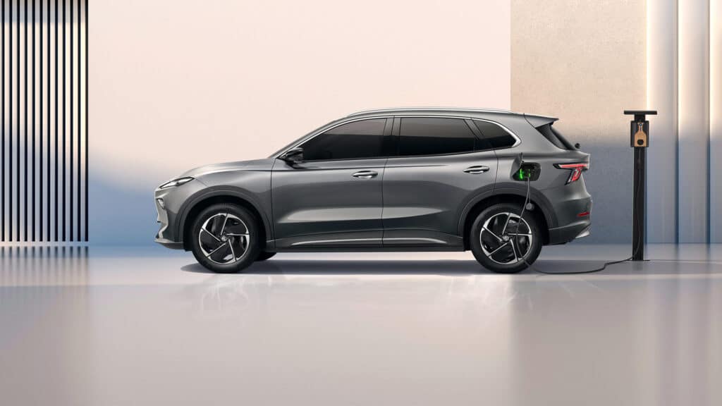 Auf diesem Bild ist ein graues Elektro-SUV in einer modernen Umgebung zu sehen, das an einer Ladestation aufgeladen wird.