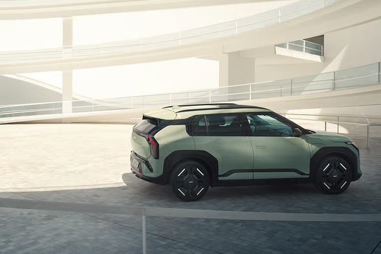 Auf diesem Bild ist ein moderner, hellgrüner SUV vor der Kulisse einer hellen und minimalistischen Architektur zu sehen.