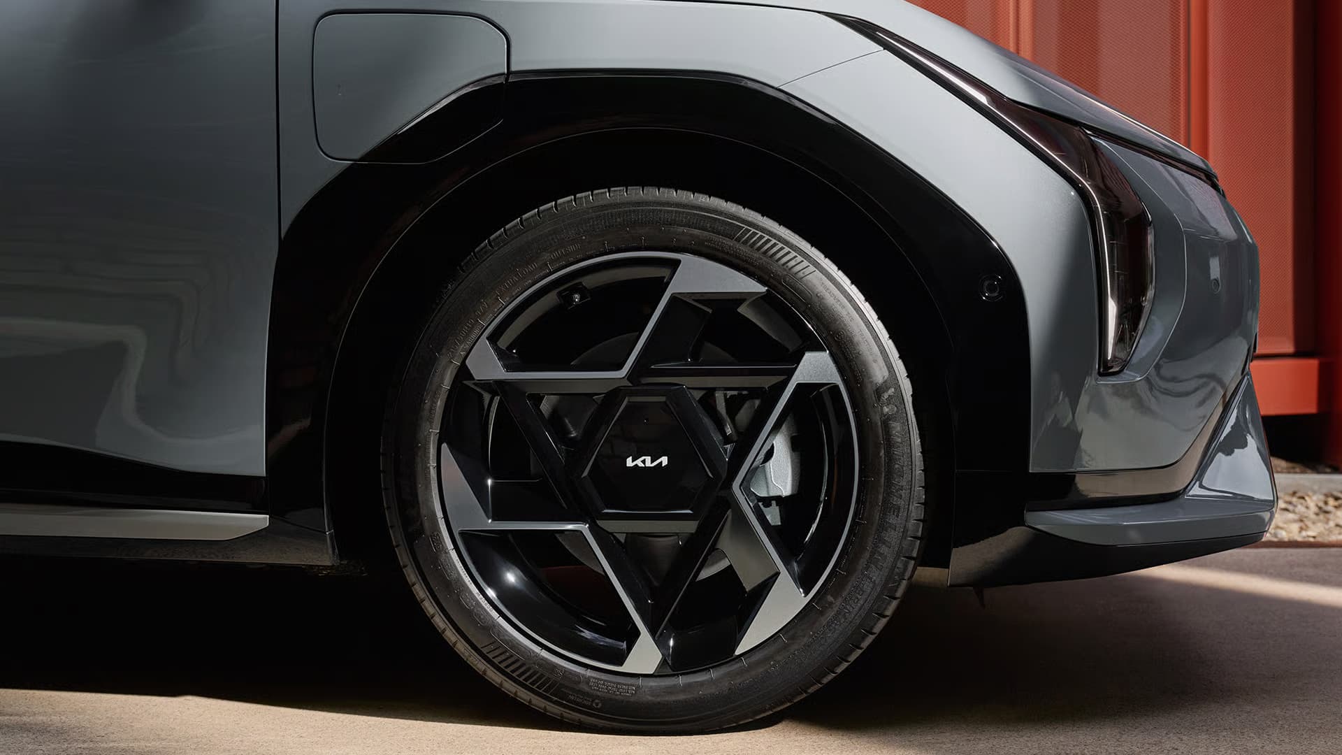 Das Bild zeigt eine Detailansicht der Frontpartie eines grauen Kia Elektroautos mit seinem auffälligen Vorderrad.