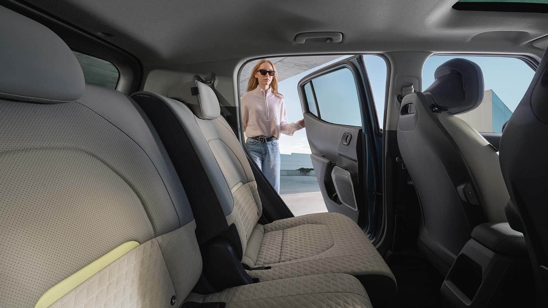 Rückbank im Innenraum des Kia EV2 Elektro-SUV mit hellen Stoffsitzen und geöffneter Fondtür.