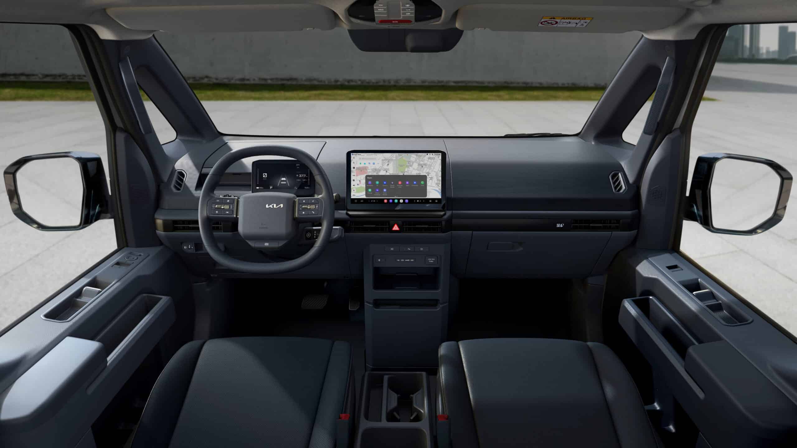 Kia PV5 Cargo Elektro-Van Interior: Frontale Ansicht des Fahrerbereichs mit digitalem Cockpit und Infotainment-System.